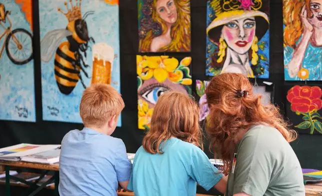 A family participate in a painting workshop during the Red Head Days festival in Tilburg, Netherlands, Saturday, Aug. 30, 2025. (AP Photo/Virginia Mayo)
