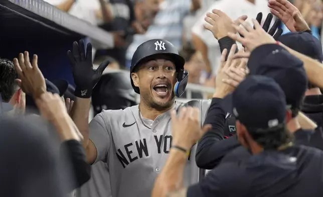 New York Yankees designated hitter Giancarlo Stanton (27) celebrates with teammates after hitting a three-run homer in the fourth inning of a baseball game against the Miami Marlins, Friday, Aug. 1, 2025, in Miami. (AP Photo/Rebecca Blackwell)