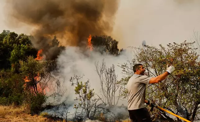 A man tries to put out a wildfire in Larouco, northwestern Spain, Wednesday, Aug. 13, 2025. (AP Photo/Lalo R. Villar)