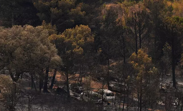 Cars and burned trees are pictured during one of the largest wildfire in decades in Fontjoncouse, southern France, Friday, Aug. 8, 2025. (AP Photo/Manu Fernandez)