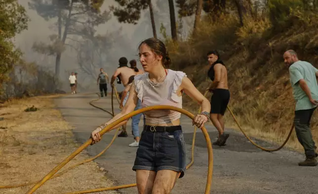 Local residents and volunteers try to put out a wildfire in Larouco, northwestern Spain, Wednesday, Aug. 13, 2025. (AP Photo/Lalo R. Villar)