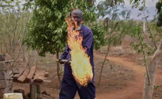 Richard Shika demonstrates how he uses fire to scare away elephants around his farm in Voi town, Taita-Taveta County, Kenya, on Aug. 6, 2024. (AP Photo/Brian Inganga)