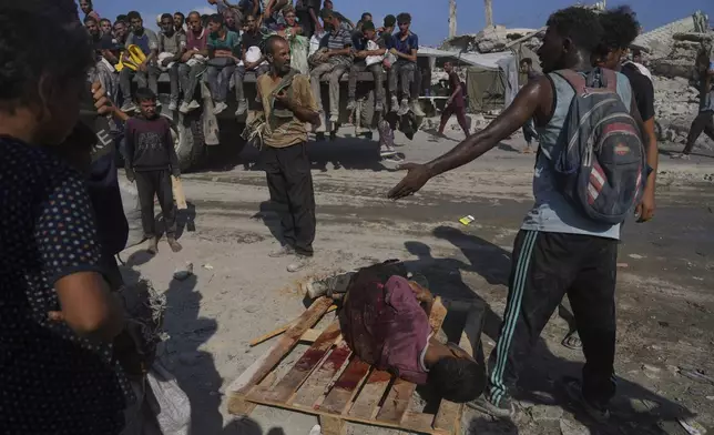 Palestinians carry a man injured while trying to reach a humanitarian aid convoy on the outskirts of Beit Lahiya in the northern Gaza Strip, Saturday, Aug. 23, 2025. (AP Photo/Abdel Kareem Hana)