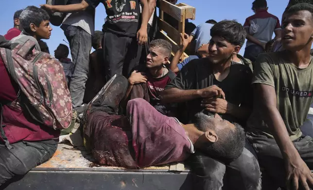 Palestinians, including an injured man, ride on an aid truck returning to Gaza City from the northern Gaza Strip, Saturday, Aug. 23, 2025. (AP Photo/Abdel Kareem Hana)