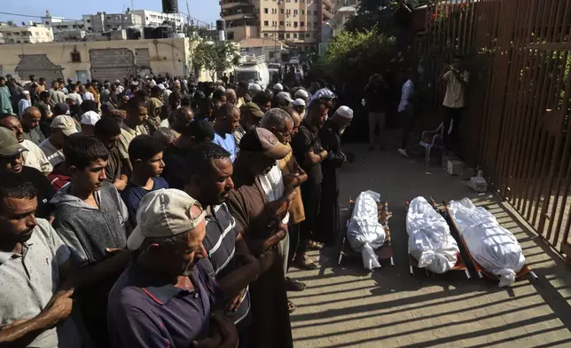 Mourners pray over the bodies of three Palestinians, killed along with others in Israeli strikes, during their funeral outside Nasser Hospital in Khan Younis, southern Gaza Strip, Saturday, Aug. 23, 2025. (AP Photo/Mariam Dagga)