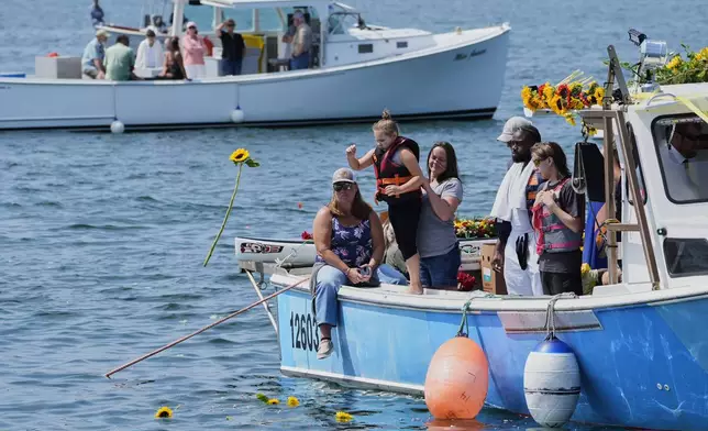 A girl tosses a sunflower into the water in honor of Sunshine Stewart, Sunday, Aug. 10, 2025, in St. George, Maine. (AP Photo/Robert F. Bukaty)