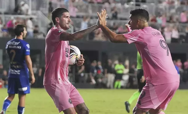 Inter Miami midfielder Rodrigo De Paul, left celebrates with forward Luis Suárez (9) after scoring a goal during the first half of a Leagues Cup soccer match against Puma UNAM, Wednesday, Aug. 6, 2025, in Fort Lauderdale, Fla. (AP Photo/Lynne Sladky)