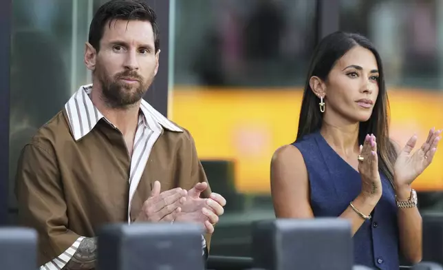 Inter Miami forward Lionel Messi, left, sits with his wife Antonela Roccuzzo, right, before a Leagues Cup soccer match against Pumas UNAM, Wednesday, Aug. 6, 2025, in Fort Lauderdale, Fla. (AP Photo/Lynne Sladky)