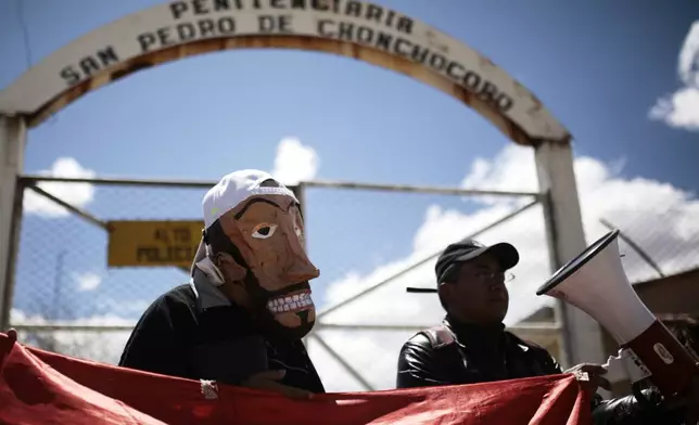 A supporter of opposition leader Luis Fernando Camacho wears a mask in his likeness outside the jail as he awaits the leader's release from jail who was allowed house arrest after almost three years in pretrial detention for his involvement in violent unrest that led to the 2019 ouster of then-President Evo Morales, in La Paz, Bolivia, Friday, Aug. 29, 2025. (AP Photo/Gaston Brito)