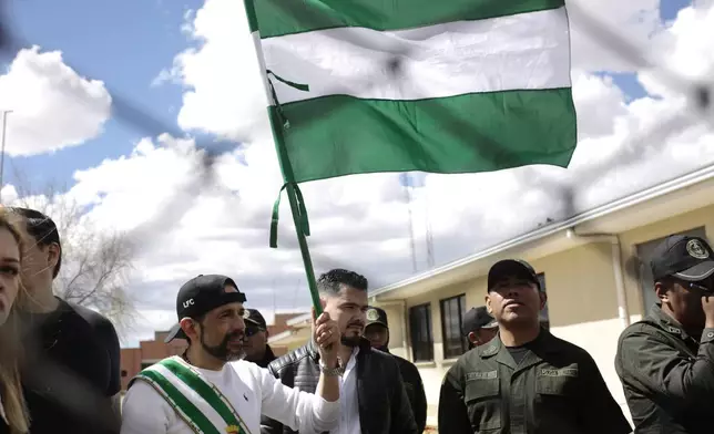 Opposition leader Luis Fernando Camacho, the suspended governor of Santa Cruz, holds up his department's flag as he is released from jail and allowed house arrest after almost three years in pretrial detention for his involvement in violent unrest that led to the 2019 ouster of then-President Evo Morales, in La Paz, Bolivia, Friday, Aug. 29, 2025. (AP Photo/Gaston Brito)
