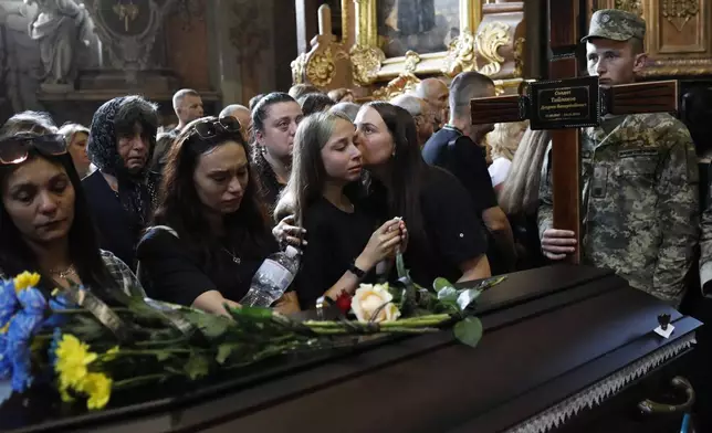 People say the last goodbye to 12 Ukrainian soldiers who died in Russian captivity during a funeral ceremony in central Lviv, Ukraine, Friday, July 25, 2025. (AP Photo/Mykola Tys)