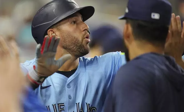 Toronto Blue Jays' George Springer celebrates scoring a run in the 12th inning during a baseball game against the Miami Marlins, Saturday, Aug. 23, 2025, in Miami. (AP Photo/Jim Rassol)