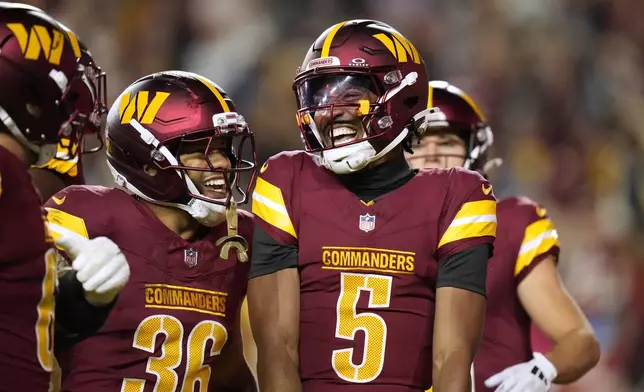 Washington Commanders quarterback Jayden Daniels (5) is congratulated by teammate Chris Rodriguez Jr. (36) after scoring during the first half of a preseason NFL football game Monday, Aug. 18, 2025, in Landover, Md. (AP Photo/Stephanie Scarbrough)