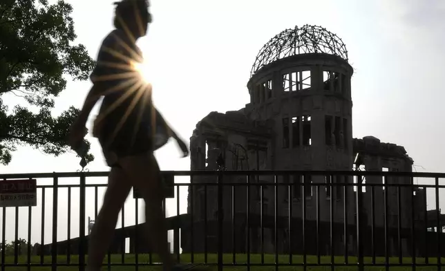 A foreign visitor walks by the iconic exhibition hall best known as the Atomic Bomb Dome on Wednesday, July 9, 2025, in Hiroshima, western Japan. (AP Photo/Eugene Hoshiko)