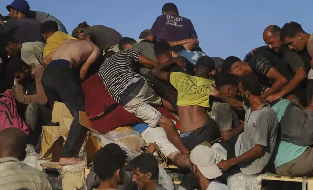 Palestinians ride on a truck loaded with food and humanitarian aid as it moves along the Morag corridor near Rafah, in the southern Gaza Strip, Monday, Aug. 4, 2025. (AP Photo/Mariam Dagga)