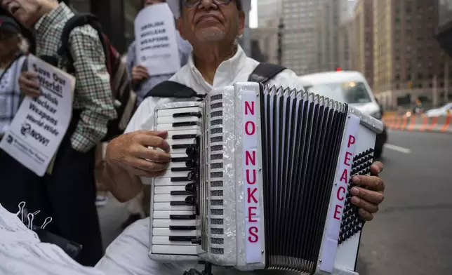A person holds an accordion with a sign reading "No Nukes Peace" during a peace gathering outside Consulate General of Japan, Tuesday, Aug. 5, 2025, in New York. (AP Photo/Yuki Iwamura)