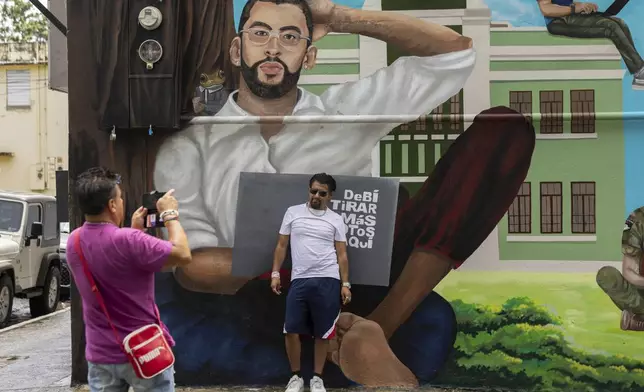 A visitor on a guided tour poses for a photo in front of a mural of Bad Bunny in Vega Baja, Puerto Rico, Tuesday, Aug. 12, 2025. (AP Photo/Alejandro Granadillo)