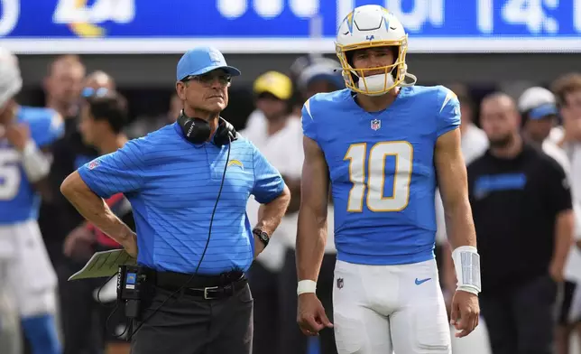 Los Angeles Chargers head coach Jim Harbaugh, left, and quarterback Justin Herbert (10) watch as wide receiver Quentin Johnston is tended to during the first half of an NFL preseason football game against the Los Angeles Rams, Saturday, Aug. 16, 2025, in Inglewood, Calif. (AP Photo/Mark J. Terrill)