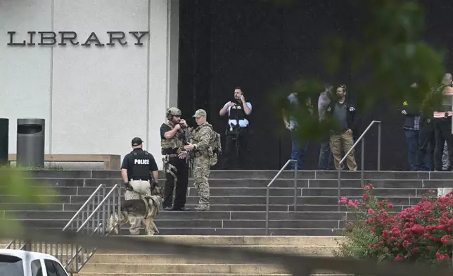 Law enforcement officers gather in front of the library on the University of Arkansas campus while responding to reports of a shooting Monday, Aug. 25, 2025, in Fayetteville, Ark. (AP Photo/Michael Woods)