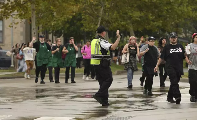 University of Arkansas students and employees evacuate and take shelter Monday, Aug. 25, 2025, in Fayetteville, Ark., as police respond to reports of a shooting. (AP Photo/Michael Woods)
