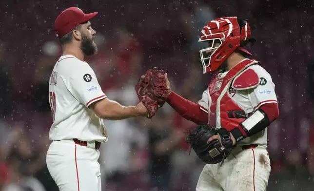 Cincinnati Reds pitcher Sam Moll, left, and Cincinnati Reds catcher Jose Trevino celebrate after winning a baseball game against the Philadelphia Phillies Tuesday, Aug. 12, 2025, in Cincinnati. (AP Photo/Carolyn Kaster)