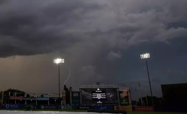 A lightning bolt strikes beyond the outfield wall delaying the start of a baseball game between the Tampa Bay Rays and the New York Yankees Tuesday, Aug. 19, 2025, in Tampa, Fla. (AP Photo/Chris O'Meara)