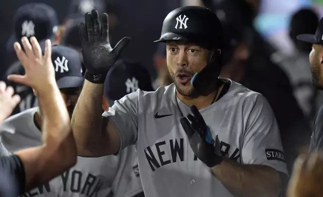 New York Yankees' Giancarlo Stanton celebrates in the dugout after hitting a solo home run off Tampa Bay Rays pitcher Shane Baz during the first inning of a baseball game Tuesday, Aug. 19, 2025, in Tampa, Fla. (AP Photo/Chris O'Meara)