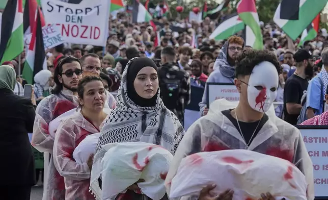 Protesters carry bloodied artificial babies to symbolize children killed in Gaza during a pro Palestine demonstration in Frankfurt, Germany, Saturday, Aug.30, 2025. (AP Photo/Michael Probst)