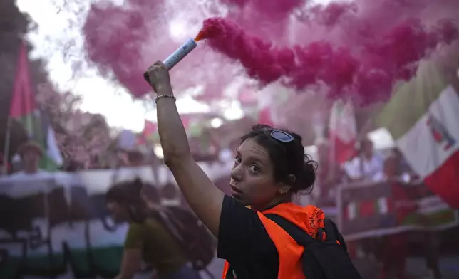 A demonstrator holds a pink flare during a march in support of the Palestinian people in Gaza, during the Film Festival in Venice, Italy, Saturday, Aug. 30, 2025. (Photo by Alessandra Tarantino/Invision/AP)