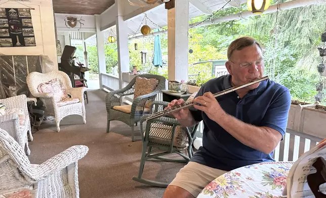 Retired cardiologist Dr. Joe Bering teaches himself flute on the front porch of his cottage in the Campmeeting section of Mount Gretna, Pa., Wednesday, Aug. 6, 2025. (AP Photo/Mark Scolforo)