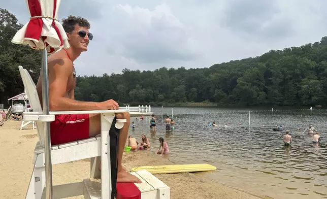 Lifeguard Luke Macchione watches over swimmers and boaters Wednesday, Aug. 6, 2025, on Lake Conewago in Mount Gretna, Pa., a town that springs to life every summer, when its picturesque front porches become filled with energetic cottagers. (AP Photo/Mark Scolforo)