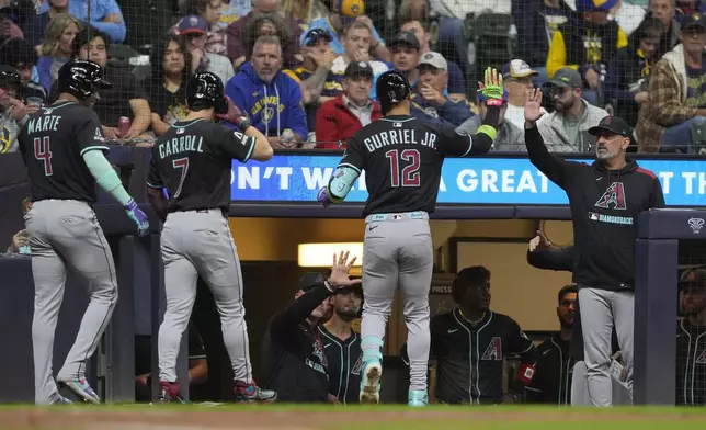 Arizona Diamondbacks' Lourdes Gurriel Jr. (12) is congratulated at the dugout after hitting a three-run home run during the fifth inning of a baseball game against the Milwaukee Brewers, Monday, Aug. 25, 2025, in Milwaukee. (AP Photo/Aaron Gash)