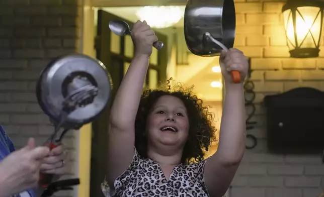 Joan Ratner bangs a pot on her porch in protest of President Donald Trump's use of federal law enforcement and National Guard troops in Washington, Wednesday, Aug. 20, 2025, in Washington. (AP Photo/Julia Demaree Nikhinson)