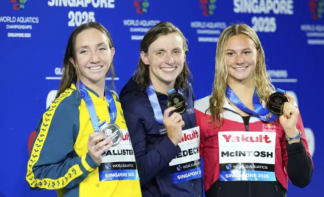 Gold medalist Katie Ledecky of the United States, center, flanked by silver medalist Lani Pallister of Australia, left, and bronze medalist Summer McIntosh of Canada pose on the podium after the women's 800-meter freestyle final at the World Aquatics Championships in Singapore, Saturday, Aug. 2, 2025. (AP Photo/Vincent Thian)