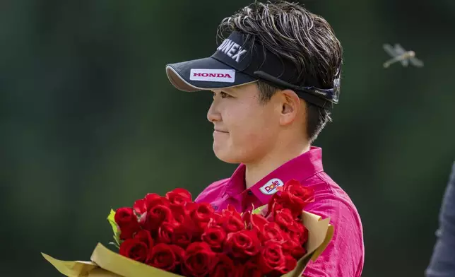 Akie Iwai, of Japan, holds a bouquet of flowers after winning the LPGA Portland Classic golf tournament at Columbia Edgewater in Portland, Ore., Sunday, Aug. 17, 2025. (AP Photo/Ali Gradischer)