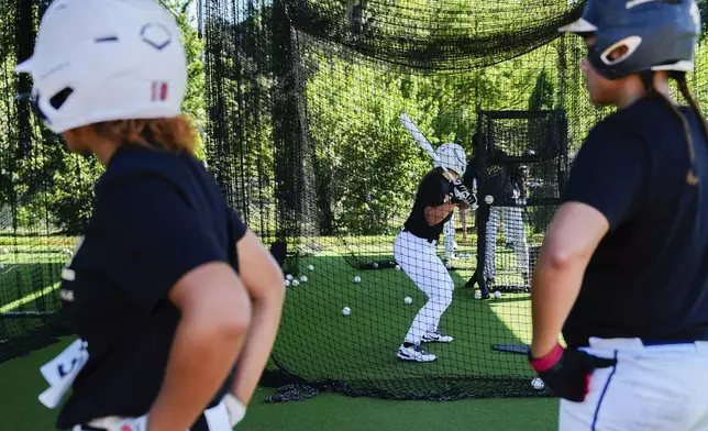 A player hits in a batting cage as others watch during the first day of tryouts for the Women's Professional Baseball League, Friday, Aug 22, 2025, at the Washington Nationals Youth Baseball Academy in Washington. (AP Photo/Julia Demaree Nikhinson)