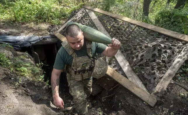 A soldier of Ukraine's 30th Mechanized Brigade prepares to fire a howitzer towards Russian positions on the front line near near Kharkiv, Ukraine, Wednesday, Aug. 13, 2025. (AP Photo/Andrii Marienko)