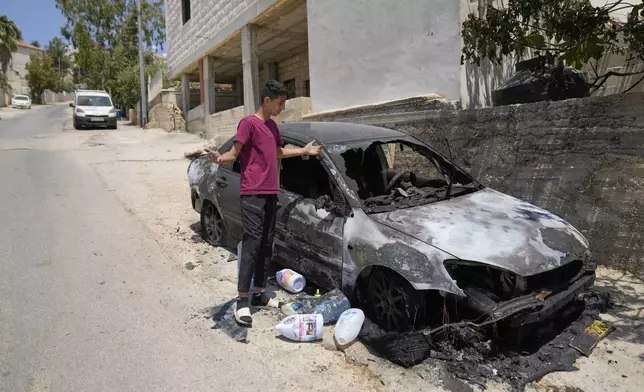 A resident inspects a torched vehicle following a spree of violent rampage by Israeli settlers overnight that left one dead Palestinian American, a burnt house and several torched vehicles in three Palestinian towns, in the West Bank town of Rammun, east of Ramallah Thursday, July 31, 2025. (AP Photo/Nasser Nasser)