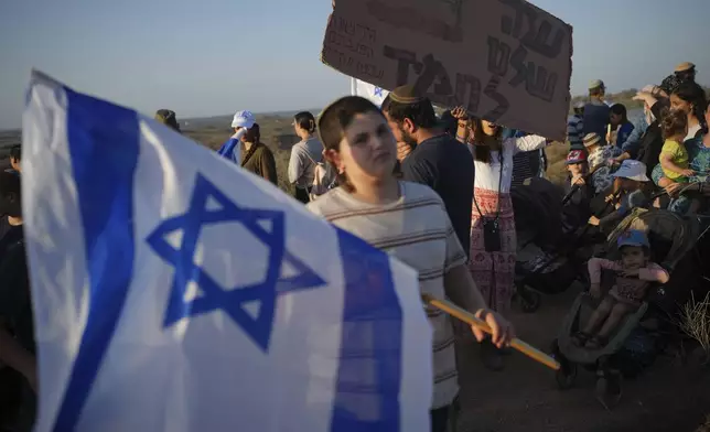 Israeli right-wing activists, one holding a sign ""Gaza is ours forever," attend a rally calling for the re-establishment of Jewish settlements in the Gaza Strip, near the border in southern Israel, Wednesday, July 30, 2025. (AP Photo/Ohad Zwigenberg)