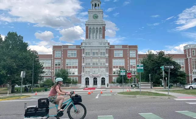 A cyclist rides past East High School in Denver on Thursday, Aug. 28, 2025. (AP Photo/Thomas Peipert)