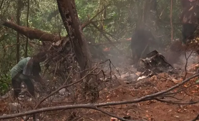 In this image taken from video, people work at the site of a military helicopter crash in Sikaman near Adansi, Ashanti region, Ghana, Wednesday, Aug. 6, 2025. (AP Photo/Hafiz Tijani)