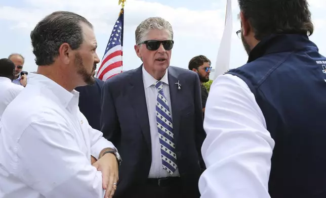 Rhode Island Gov. Dan McKee, center, speaks with Laborers' International Union of North America leaders Donato Bianco, left, and Michael Sabitoni, right, after a news conference in North Kingstown, R.I., on Monday, Aug. 25, 2025. Democratic politicians and union leaders called on the Trump administration to allow work to continue on the Revolution Wind offshore wind farm. (AP Photo/Jennifer McDermott)