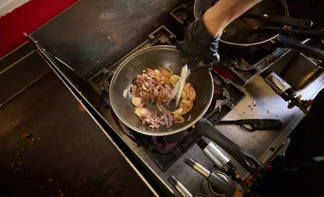 A person cooks inside the Stejk Street Food truck in Kiruna, Sweden, Sunday, Aug. 17, 2025. (AP Photo/Malin Haarala)