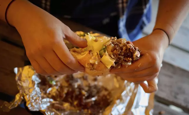 A person holds a sandwich at the Stejk Street Food food place in Kiruna, Sweden, Sunday, Aug. 17, 2025. (AP Photo/Malin Haarala)