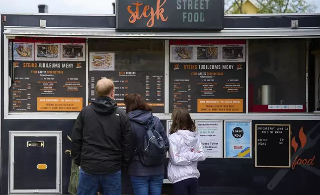 Customers look at the menus outside the Stejk Street Food truck in Kiruna, Sweden, Sunday, Aug. 17, 2025. (AP Photo/Malin Haarala)