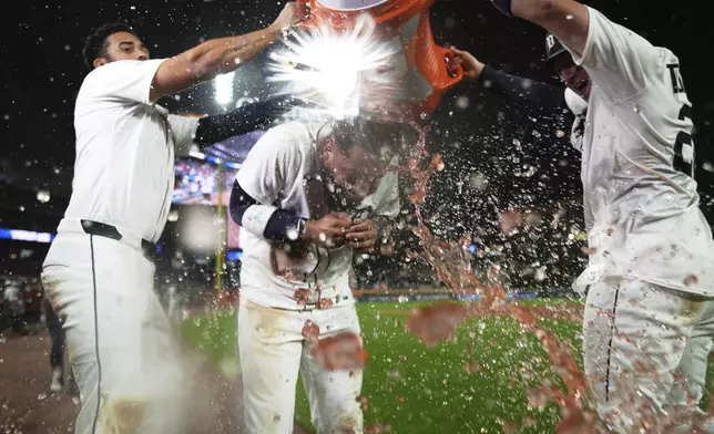 Detroit Tigers' Gleyber Torres, center, is dunked by Riley Greene, left, and Spencer Torkelson after drawing a bases-loaded walk to win a baseball game against the Houston Astros in the 10th inning, Tuesday, Aug. 19, 2025, in Detroit. (AP Photo/Ryan Sun)