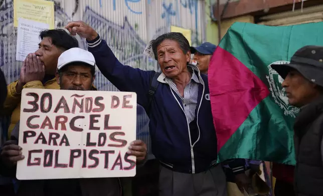 A protester holds a sign that reads in Spanish, "30 years in prison for the coup plotters" as suspended governor of Santa Cruz Luis Fernando Camacho attends a court hearing regarding the length of his pretrial detention stemming from the crisis over the 2019 ouster of former President Evo Morales, in La Paz, Bolivia, Tuesday, Aug. 26, 2025. (AP Photo/Juan Karita)