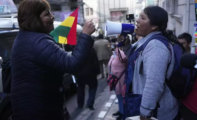 A supporter of suspended Santa Cruz Governor Luis Fernando Camacho blocks an anti-Camacho demonstrator, right, during a court hearing regarding the length of Camacho's pretrial detention stemming from the crisis over the 2019 ouster of former President Evo Morales, in La Paz, Bolivia, Tuesday, Aug. 26, 2025. (AP Photo/Juan Karita)