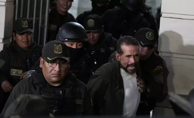 Former governor of Santa Cruz Luis Fernando Camacho is escorted by police as he leaves a court hearing regarding the length of his pretrial detention stemming from the crisis over the 2019 ouster of former President Evo Morales, in La Paz, Bolivia, Tuesday, Aug. 26, 2025. (AP Photo/Juan Karita)