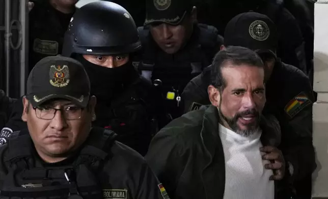 Former governor of Santa Cruz Luis Fernando Camacho is escorted by police as he leaves a court hearing regarding the length of his pretrial detention stemming from the crisis over the 2019 ouster of former President Evo Morales, in La Paz, Bolivia, Tuesday, Aug. 26, 2025. (AP Photo/Juan Karita)